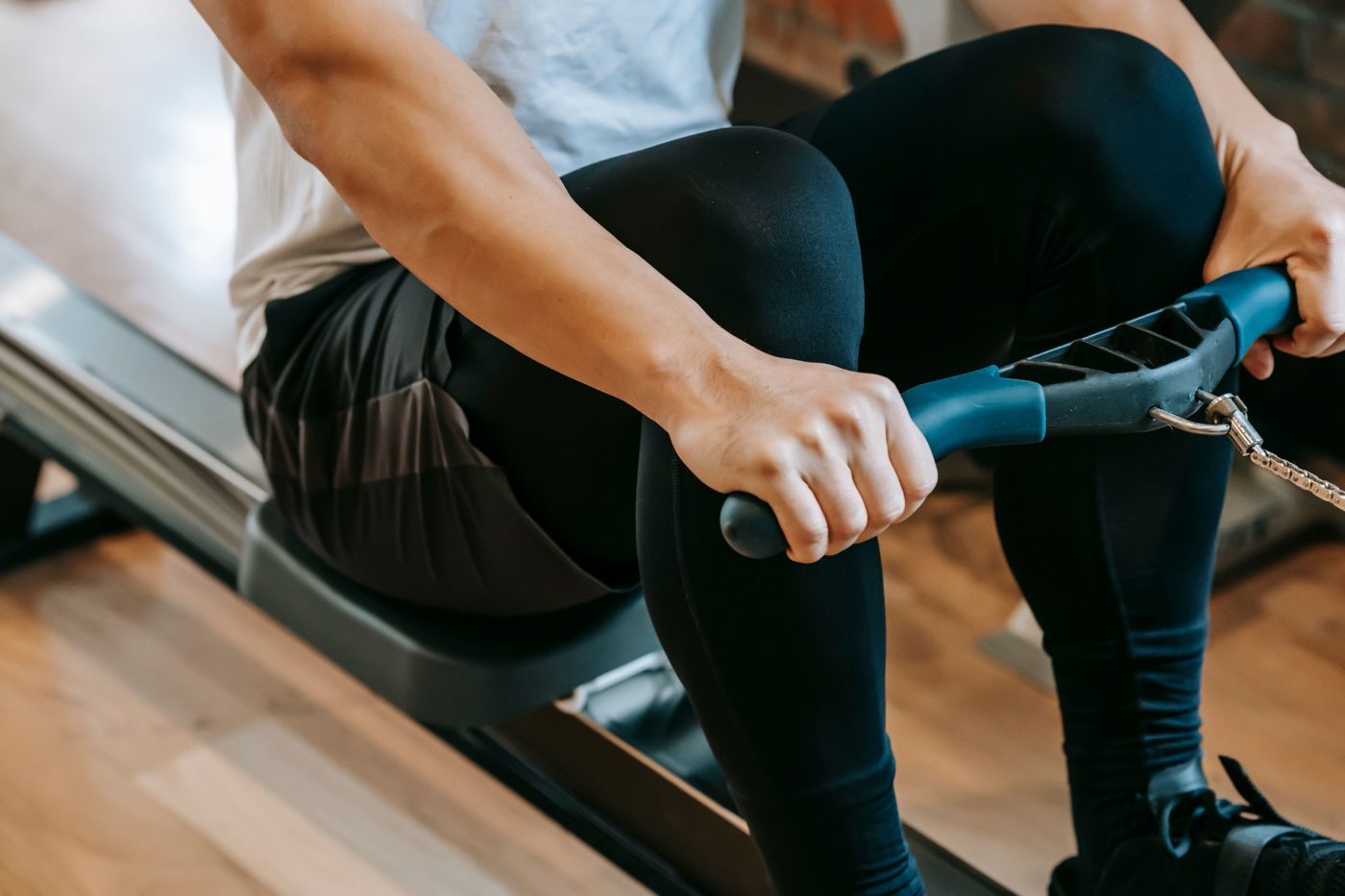 Person rowing on an indoor rowing machine, hands on the handle