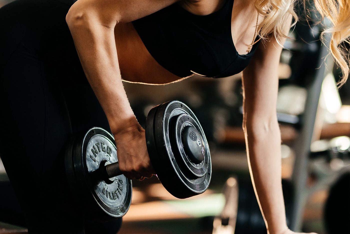 Person performing a one-arm dumbbell row in a gym